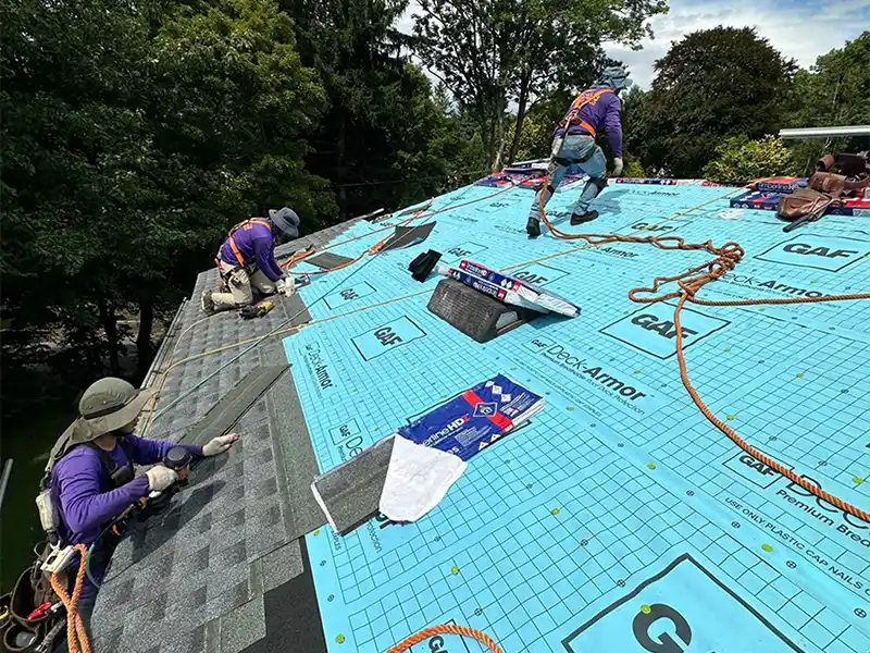 Crew installing new shingles on roof